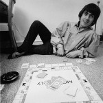 George Harrison playing monopoly during the Beatles tour of the USA. at rented Bel Air home with Jackie de Shannon (out of shot) August 1964