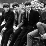 The Beatles pose sitting on a wall, 1963